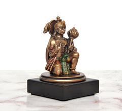 Resin Hanuman idol angled view, seated with one hand holding mace, on pedestal base.