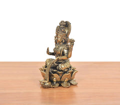 Seated Lakshmi idol from side, flowing jewelry details and lotus base