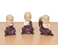 Set of three purple resin monk Buddha figurines, seated poses, straight-on view