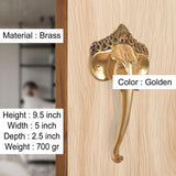 Brass Ganesha face door handle on a wood door, ornate circular rosette plates