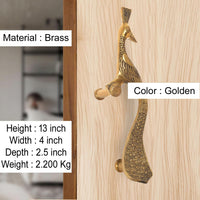 Golden brass peacock-style door handle with leaf-pattern detailing on wood