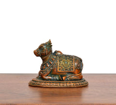 Side view of seated Nandi brass figurine with embossed jewelry-like motifs