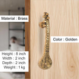 Brass sitar-shaped door handle pair, golden finish, mounted on a door panel
