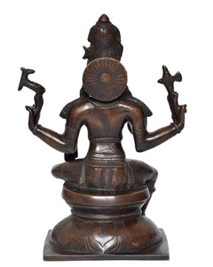 Back view of Lord Shiva statue, seated with detailed round back ornament and trident arms, dark brass