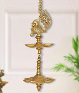 Brass hanging peacock oil diya with chain, decorative peacock atop tiered lamp bowls