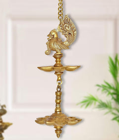 Brass hanging peacock oil diya with chain, decorative peacock atop tiered lamp bowls