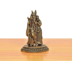 Brass Radha Krishna idol from side-back: Krishna plays flute with Radha close by