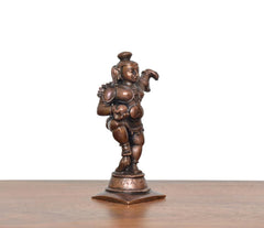 Copper dancing Bal Krishna figure holding laddu, back angle on square base