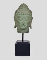 Close-up bronze Buddha head idol on black base, calm eyes and lips