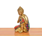 Side view of brass seated Buddha idol with multicolor jeweled robe