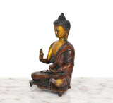 Brass Buddha idol side view, Abhaya mudra hand raised, ornate pedestal base