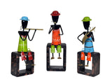 Front view: three iron musician figurines with blue, red, and green hats on block bases
