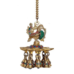 Close-up brass hanging peacock oil diya with 9 bells and enamel inlays, chain attached