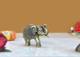 Brass elephant figurine with decorative textured back, walking side view