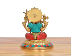 Back view of brass goddess statue with gold halo crown, teal bodice, red patterned skirt, ornate base.