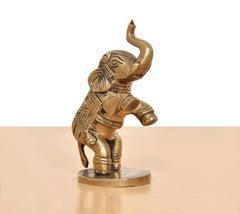 Brass elephant figurine, gold tone, side view with raised trunk, standing on round base