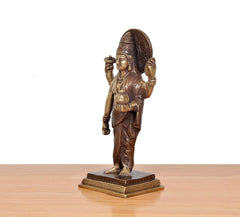 Brass Dhanvantri statue side view with raised staff arm and draped garments