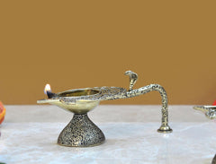 Decorative brass aarti diya, lit flame with textured pedestal and patterned spout