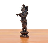 Copper Krishna playing flute murti, side/back view with intricate decorative elements.