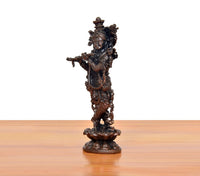 Copper Krishna playing flute murti, side/back view with intricate decorative elements.