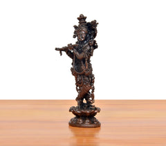 Copper Krishna playing flute murti, side/back view with intricate decorative elements.