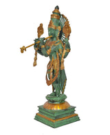Side view of green brass Krishna playing flute, gold-accented draped ornaments