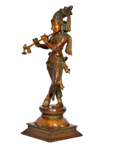 Brass Krishna statue side view, holding flute, decorated robes, pedestal base
