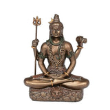 Close view of bronze Lord Shiva seated in meditation with trident and staff