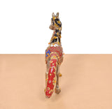 Brass running horse statue, rear view, red cloth drape with gold and blue motifs
