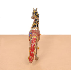 Brass running horse statue, rear view, red cloth drape with gold and blue motifs