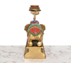 Brass elephant candle stand lamp, rear view with multicolor patterned blanket and bowl top