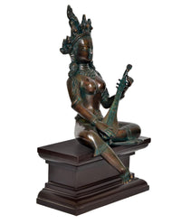 Brass Saraswati statue seated, playing veena, tall crown and halo details, pedestal