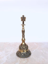 Brass pooja bell with ornate circular base, ribbed stem, Garuda top