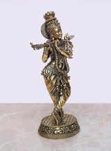 Brass Krishna idol playing flute, side view with jeweled headdress and pedestal