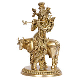 Brass Krishna with cow statue, raised flute arm and crown, standing on round base