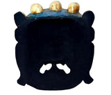 Back of wall mask with dark surface and gold-capped head details along the top