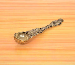 Bronze pooja spoon angled view, carved handle with curled end knob and bowl