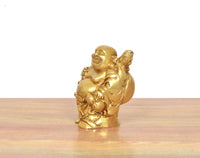 Seitenansicht: Lachender Buddha in goldfarbigem Messing, sitzendes/stehendes Gewanddetail