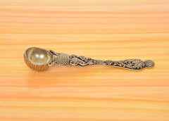 Bronze pooja spoon side view with fluted bowl rim and swirling engraved pattern