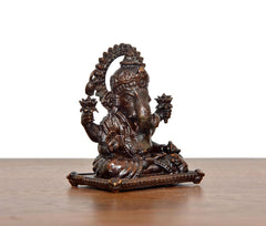Sitting Ganesha brass idol, angled view, textured torso and detailed back