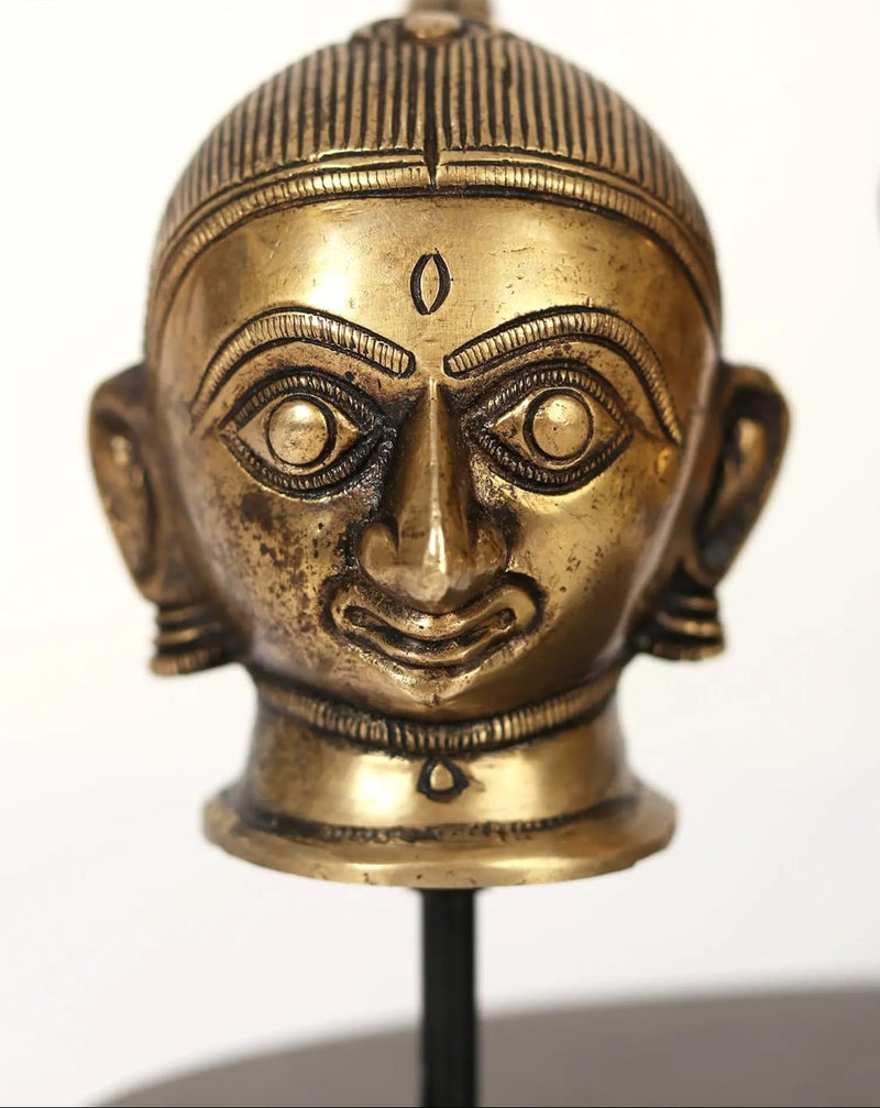 Close-up brass Gauri/Parvati head face with crown and bindi on dark base