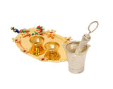 Decorated oval plate with two gold bowls, brass pichkari, and silver cup with handle