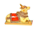 Resin Nandi cow idol close-up, yellow cow with red saddle panel and gold jewelry trim