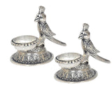 Two parrot-shaped oil diya lamps with long wings and detailed swirling engravings