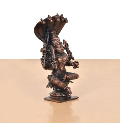 Side view of copper goddess idol statue, seated posture with cobra-hood canopy