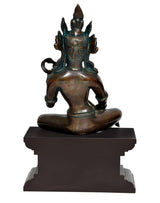 Brass Saraswati idol rear view, seated on dark wooden pedestal, ornate back crown