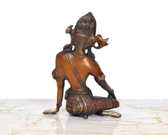 Brass Indra Devta statue from side, seated posture with patterned drape and jewelry