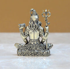 Brass Shiva seated with four arms, angled view with raised staff, textured base