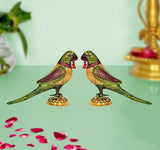 Pair of iron parrot statues with green wings and red details on gold circular bases