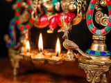 Diya tray with small flames and decorative lamp stand, Radha Krishna swing idol backdrop